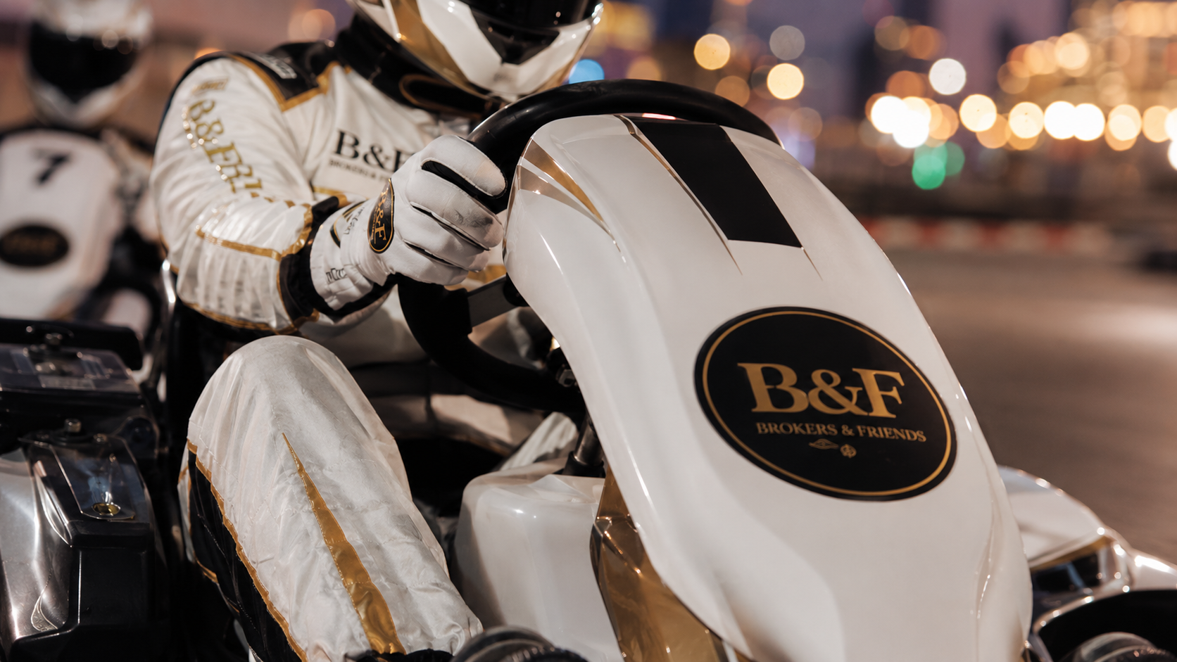 Close-up of B&F gloves on a kart steering wheel with gold branding
